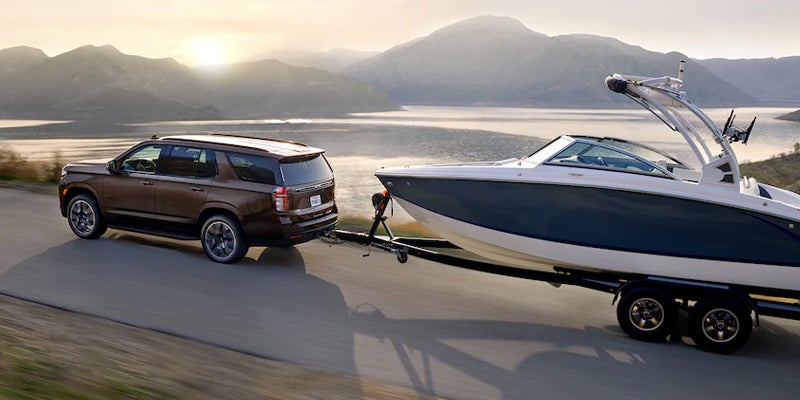 Chevrolet Tahoe driving on road towing a boat