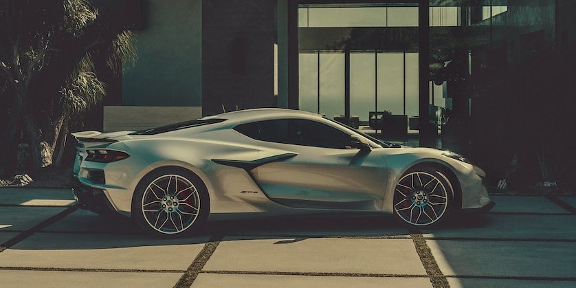 A silver Chevrolet Corvette parked front of building right side view