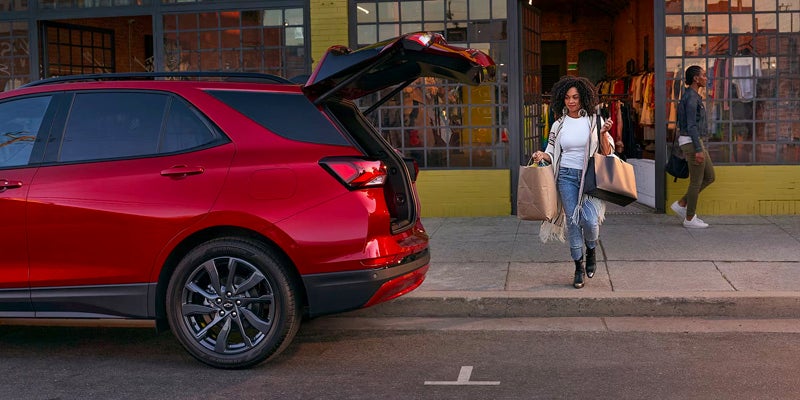 Women loading shopping bags into red SUV