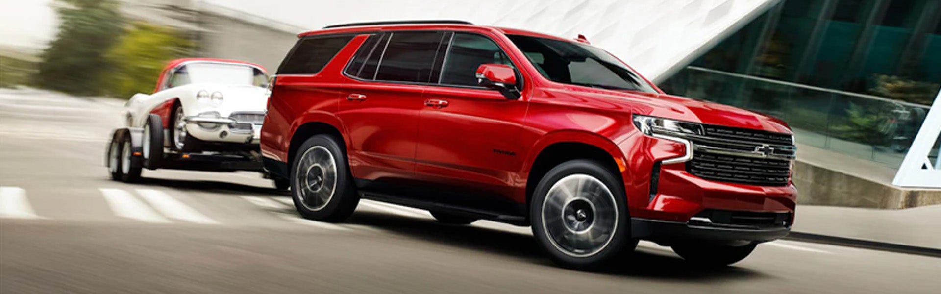 Red Chevrolet Tahoe towing an white red car