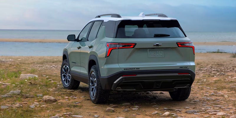 Green equinox standing on beach by turning tires to left side rear view