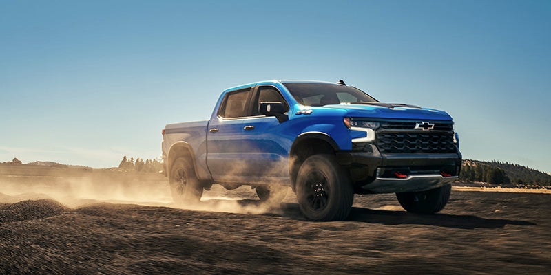 Blue Chevrolet Silverado running in desert left front view