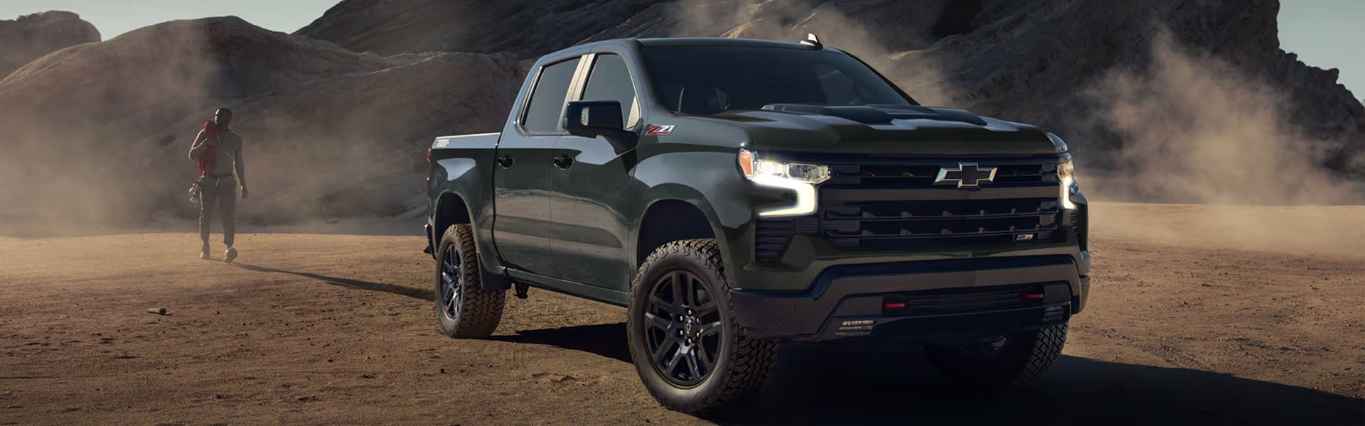 Blue Chevrolet Silverado truck running on black soils road