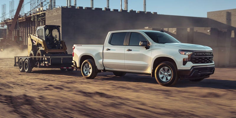 Blue Chevrolet Silverado running in desert with spreading soil front view